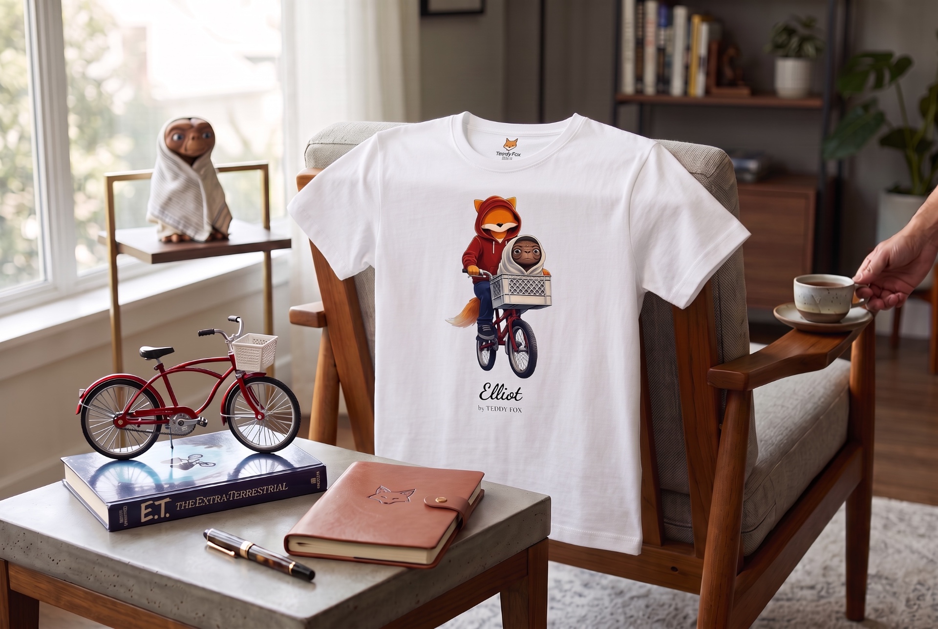 T-shirt Elliot Fox Me I’m Famous posé dans un salon, avec le renard à vélo et E.T. dans le panier